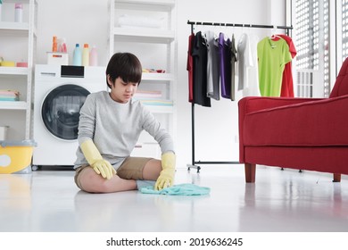 Smiling Asian Little Boy Child Is Enjoying For House Cleaning In Laundry Room. He Is Mopping The Floor. Homeschool And Family Time On Holiday Concept.