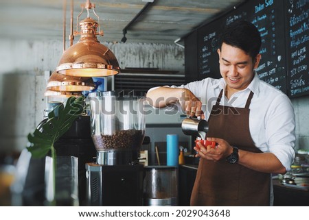 Smiling Asian man barista working at cafe.