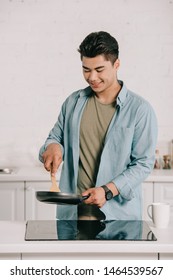 Smiling Asian Man Cooking Breakfast On Frying Pan In Kitchen