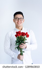 Smiling Asian Man Holding Bunch Of Roses. Young Man Looking At Camera. Flowers And Gift Concept. Isolated Front View On White Background.