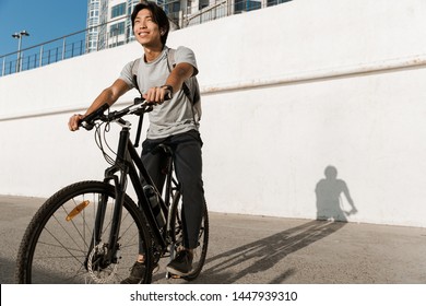 Smiling Asian Man Riding A Bicycle Outdoors