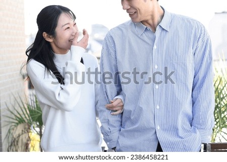 Smiling Asian man and woman couple cuddling outdoors
