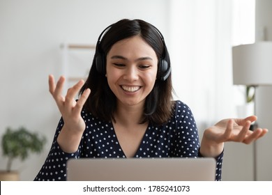 Smiling Asian Millennial  Headset Talk Speak On Video Call Using Computer At Home. Happy Vietnamese Young Woman In Headphones Have Webcam Conference Virtual Event Conversation On Laptop Online