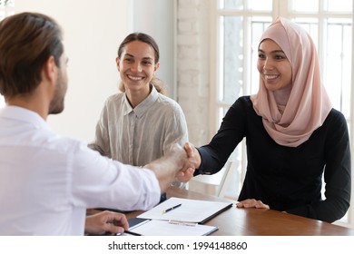 Smiling Asian Muslim Businesswoman Wearing Hijab Shaking Businessman Hand At Meeting, Celebrating Contract Signing, Diverse Business Partners Making Deal, Group Negotiations In Boardroom