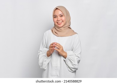 Smiling Asian Muslim woman holding hands together and feels joyful isolated over white background