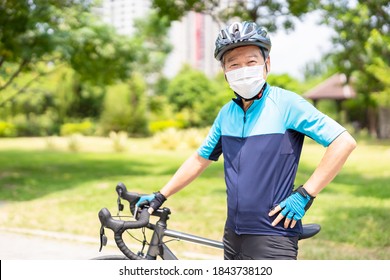 Smiling asian old man wearing helmet and face mask with bicycle is looking to you - put hands on his hips - Powered by Shutterstock