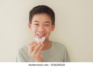 Smiling Asian Preteen Boy Holding Invisalign Braces, Mouthguard, Teen Orthodontic Oral Health Care Concept