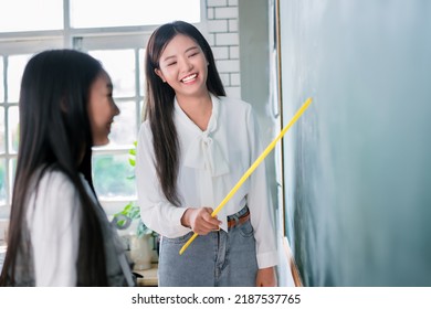 Smiling Asian Teacher Woman Teaching Student In English Classroom, Female Teacher Writing On Blackboard, High School And Back To School Concept.