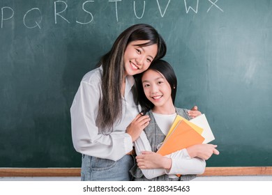 Smiling Asian Teacher Woman Teaching Student In English Classroom, Female Teacher Writing On Blackboard, High School And Back To School Concept.