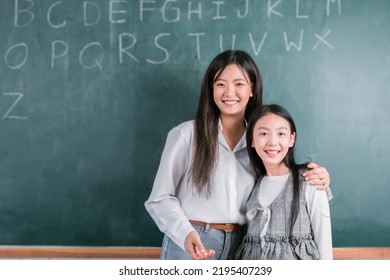 Smiling Asian Teacher Woman Teaching Student In English Classroom, Female Teacher Writing On Blackboard, High School And Back To School Concept.