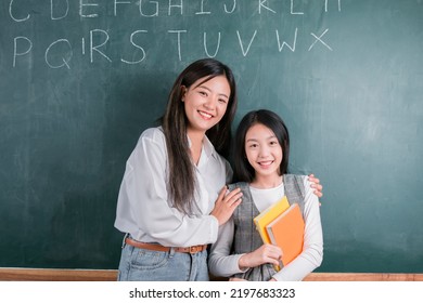 Smiling Asian Teacher Woman Teaching Student In English Classroom, Female Teacher Writing On Blackboard, High School And Back To School Concept.