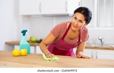 Smiling Asian Woman Cleaning Dinning Table With Rag In Kitchen At Home.