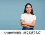 Smiling asian woman posing with crossed arms looking at camera on blue background, copy space. Advertisement concept