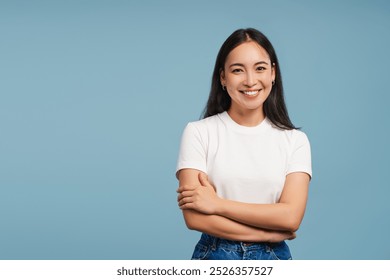 Smiling asian woman posing with crossed arms looking at camera on blue background, copy space. Advertisement concept - Powered by Shutterstock