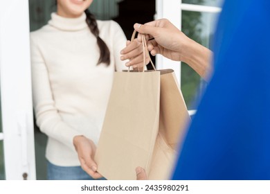 smiling Asian woman receives paper bag parcel of food from courier front house. Delivery man send deliver express. online shopping, paper container, takeaway, postman, delivery service, packages - Powered by Shutterstock