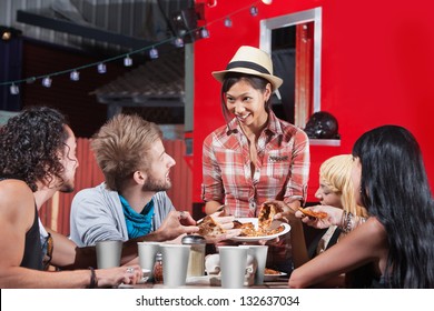 Smiling Asian Woman Sharing Pizza Slices With Friends At Food Truck