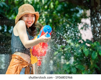 Smiling Asian Woman Was Splashed By Water. She Is Using A Water Gun For Songkran Festival.