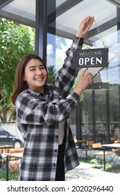 Smiling Asian Woman Turning Open Sign Broad On The Door Glass And Ready To Service.