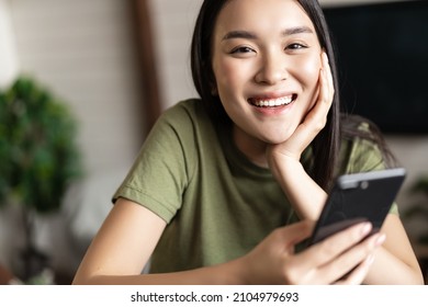 Smiling Asian Woman Using Mobile Phone From Home, Making Order, Deliver Smth To Her House