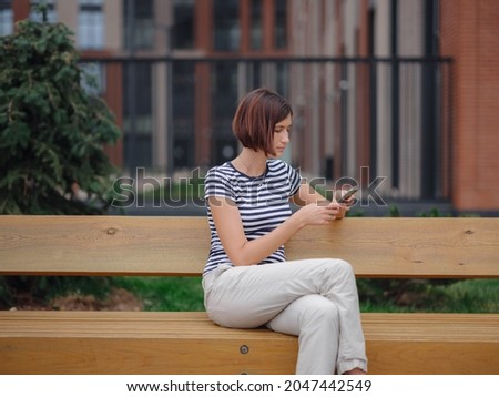 Smiling asian woman using mobile phone in the city street. checking mobile phone. student woman looking at the screen. lady e-learning via her gadget