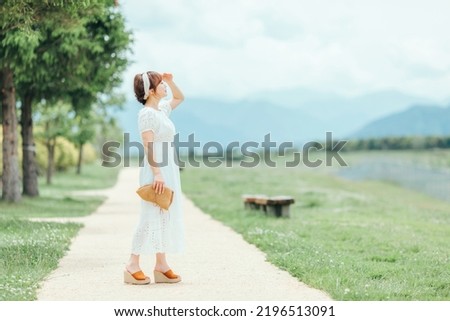 A smiling Asian woman walking in nature (ultraviolet rays, sunlight)