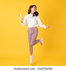 Smiling asian woman white shirt on yellow background jumping with smartphone on hand