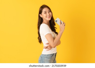 Smiling Asian Woman White Shirt On Yellow Background Using Smartphone
