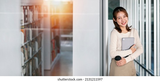 Smiling asian young woman college university school student holding laptop computer standing at library, happy teen girl looking at camera stand with device. - Powered by Shutterstock