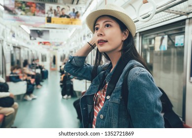 Smiling Asian Young Woman Commuter Taking Journey In Public Train Hand Holding Handle Standing. Quiet Subway People Sitting On Seat In Osaka Japan. Elegant Travel Backpacker Resting Relax In Metro.