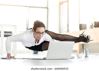 Smiling assistant doing yoga in office. She tired of sitting. Flexibility concept