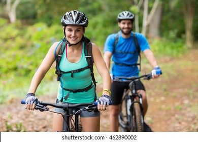 Smiling Athletic Couple Cycling In Forest