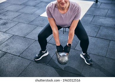 Smiling Athletic Female Performing The Two-handed Kettlebell Deadlift