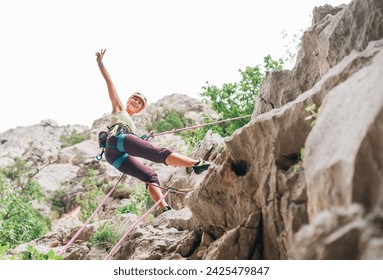 Smiling athletic woman in protective helmet and shoes climbing cliff rock wall using top rope and harness in Paklenica National park site in Croatia. Active extreme sports time spending concept - Powered by Shutterstock