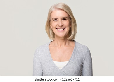 Smiling Attractive Casual Middle Aged Mature Beautiful Woman Looking At Camera, Happy Healthy Old Senior Lady With Blond Gray Hair Posing For Portrait Isolated On White Grey Blank Studio Background