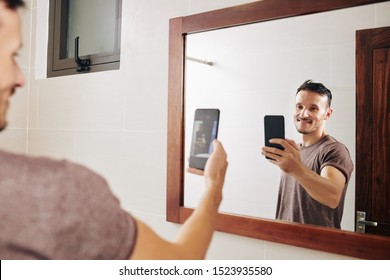 Smiling Attractive Fit Caucasian Man Taking Selfie At Bathroom Mirror