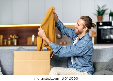 Smiling Attractive Man Unpacked His Parcel, Happy About Getting A Long Expected Order. Caucasian Modern Guy Shopping In Internet Stores, Buying New Clothes Online, Online Shopping Concept