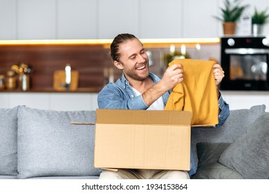 Smiling Attractive Man Unpacked His Parcel, Happy About Getting A Long Expected Order. Caucasian Modern Guy Shopping In Internet Stores, Buying New Clothes Online, Online Shopping Concept