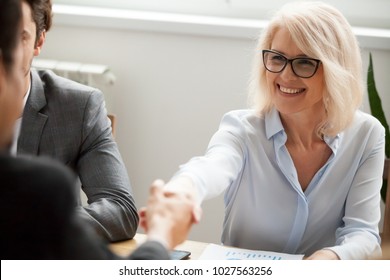 Smiling Attractive Mature Businesswoman Handshaking Businessman At Meeting Negotiation, Happy Hr Senior Executive Woman Shaking Hand Welcoming New Hire Partner, Making Deal Satisfied With Good Result