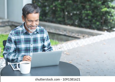 Smiling Attractive Mature Man With White, Grey Stylish Short Beard Using Smartphone Gadget Serving Internet In Modern Office,co-working Space Or Coffee Shop. Old Man Using Social Network Technology.