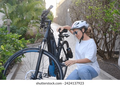 Smiling attractive mature woman with sport helmet checking her electric bicycle before to run. Healthy lifestyle concept - Powered by Shutterstock