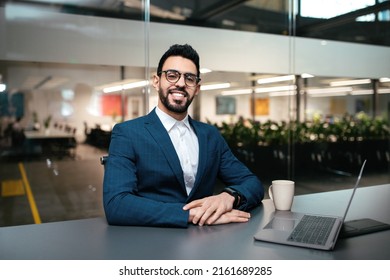 Smiling Attractive Millennial Middle Eastern Businessman With Beard In Glasses Working With Computer At Workplace In Office Interior, Copy Space. Business, Industry, Finance During Covid-19 Outbreak