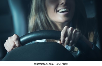 Smiling Attractive Woman Driving A Car Late At Night.