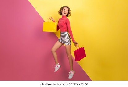 Smiling Attractive Woman In Stylish Colorful Outfit Jumping With Shopping Bags, Happy, Pink Yellow Background, Polo Neck, Striped Mini Skirt, Sale, Discount, Shopaholic, Fashion Summer Trend, Emotiona