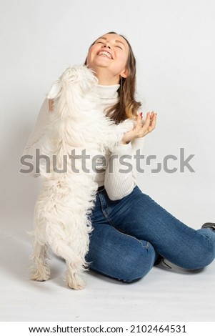 Smiling attractive young european woman in warm white jumper isolated on white with a dog