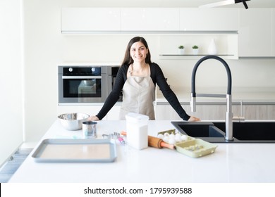 Smiling Attractive Young Woman With Baking Ingredients On Kitchen Island