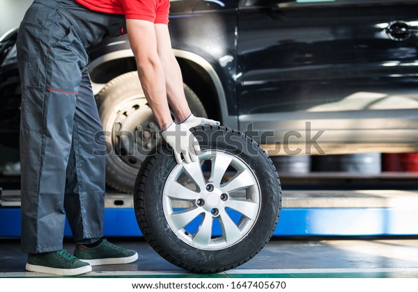 smiling auto\
mechanic carrying tire in tire\
store