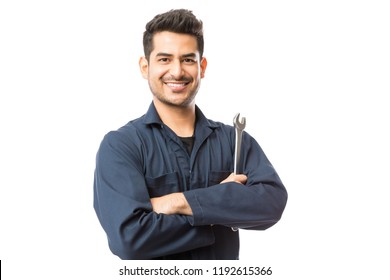 Smiling auto mechanic with wrench standing hands folded on white background