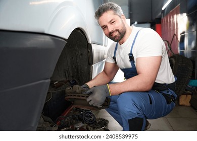 Smiling auto repair worker is posing for camera at work - Powered by Shutterstock