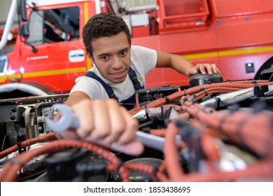 smiling automechanic repairs the engine of a lorry or bus