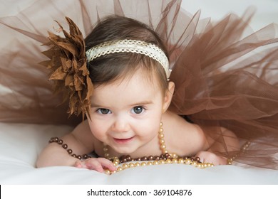 Smiling Baby Ballerina In Brown Tutu With A Pearl Necklace